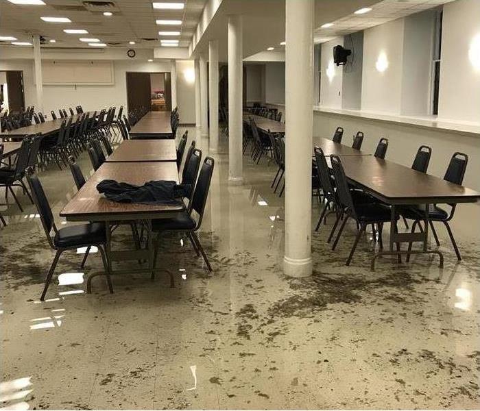 flooded cafeteria floor, debris, rows of tables and chaire